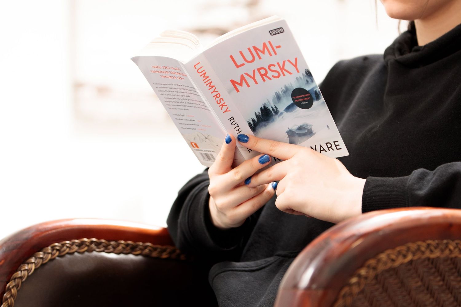 Lukupiirin osallistuja lukemassa, markkinointikuva kirjastossa