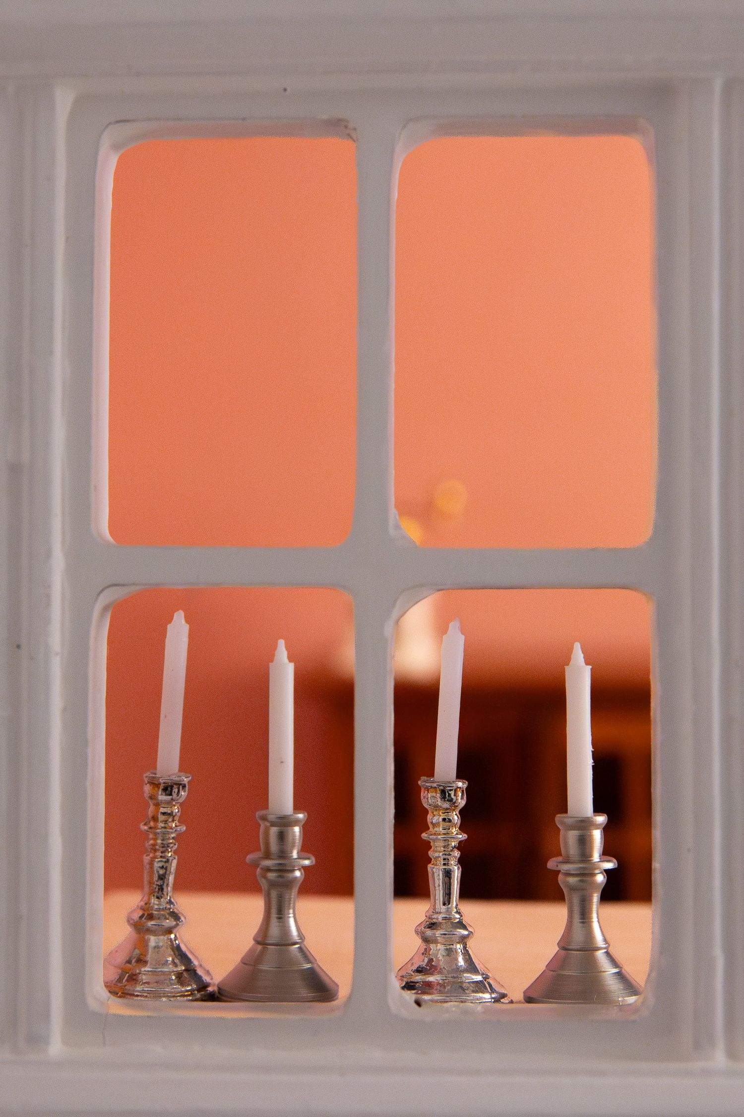 Miniatyyri-ikkuna neljällä adventtikynttilällä jouluisessa kuvassa.