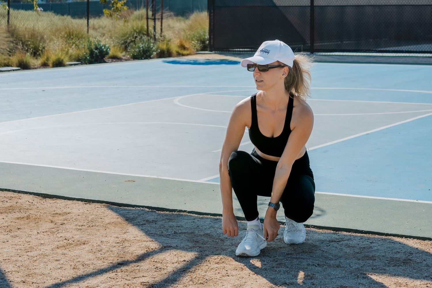 Athletes perform stretching exercises on a blue tennis court surface to warm up before playing in Laguna Beach.