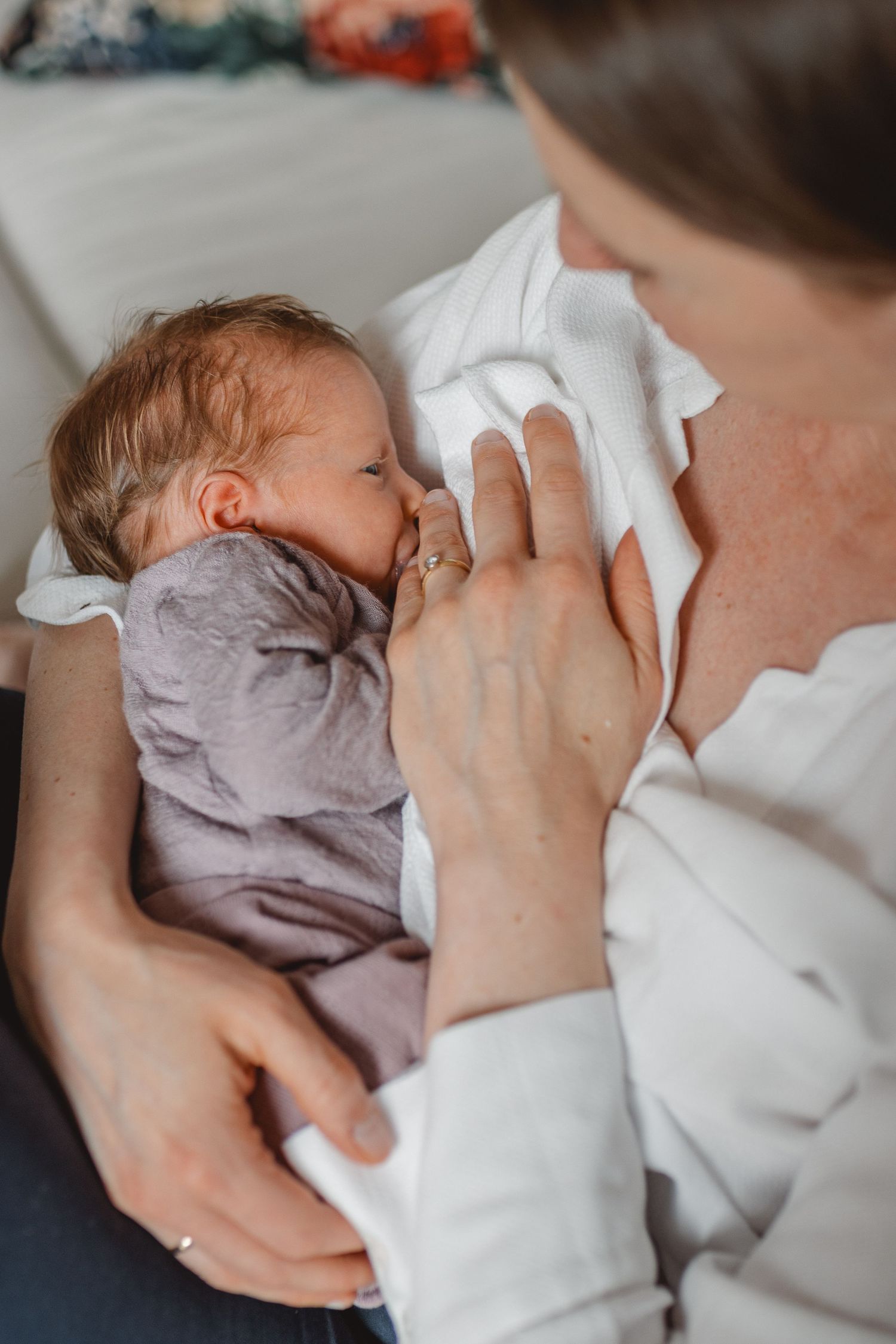 A series of intimate breastfeeding moments showing a newborn baby nursing while being cradled in soft white fabric in Laguna Beach.