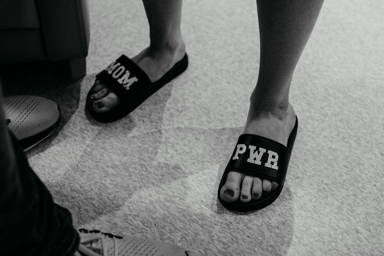 A black-and-white image of slippers with 'Mom Power' written on them in Newport Beach.