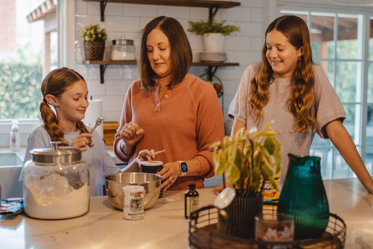 A mom with her kids gather around a table enjoying baking and conversation in a bright, modern dining space in Laguna Beach.
