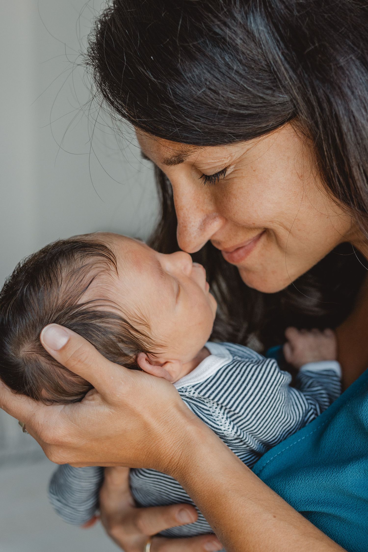 Tender moment between mother and newborn baby shown in progressive sequence of gentle kisses in Newport Beach.