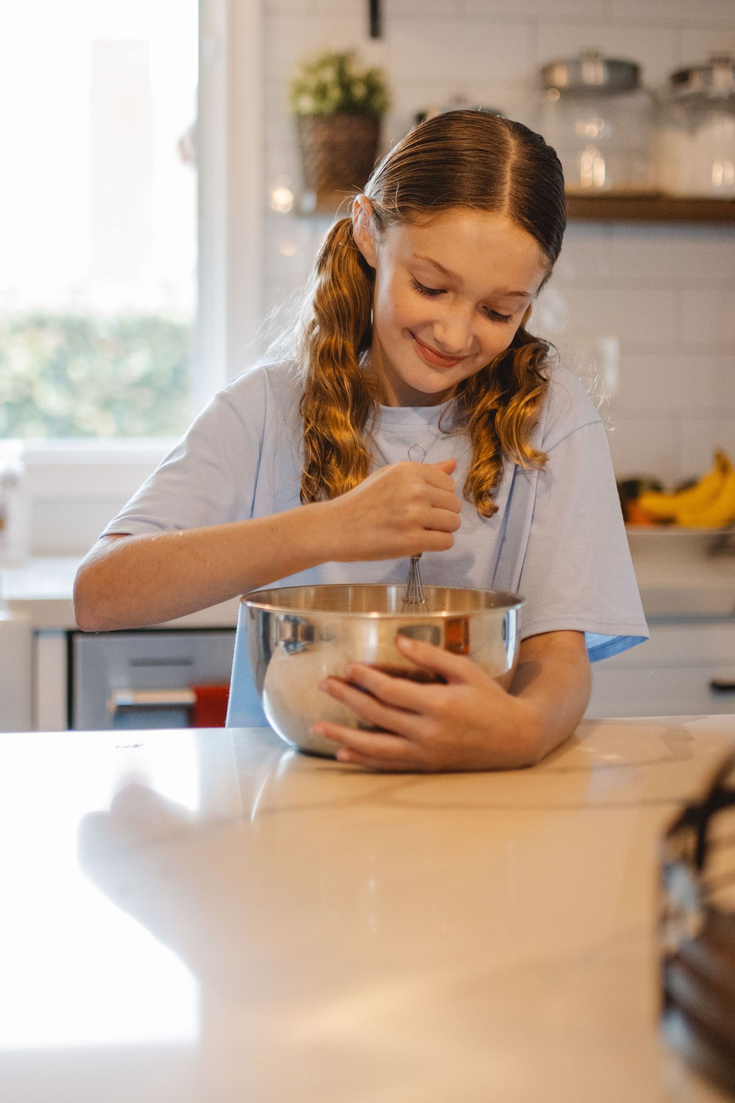 Young student in blue shirt sitting at kitchen table with natural light coming through window Huntington Beach.