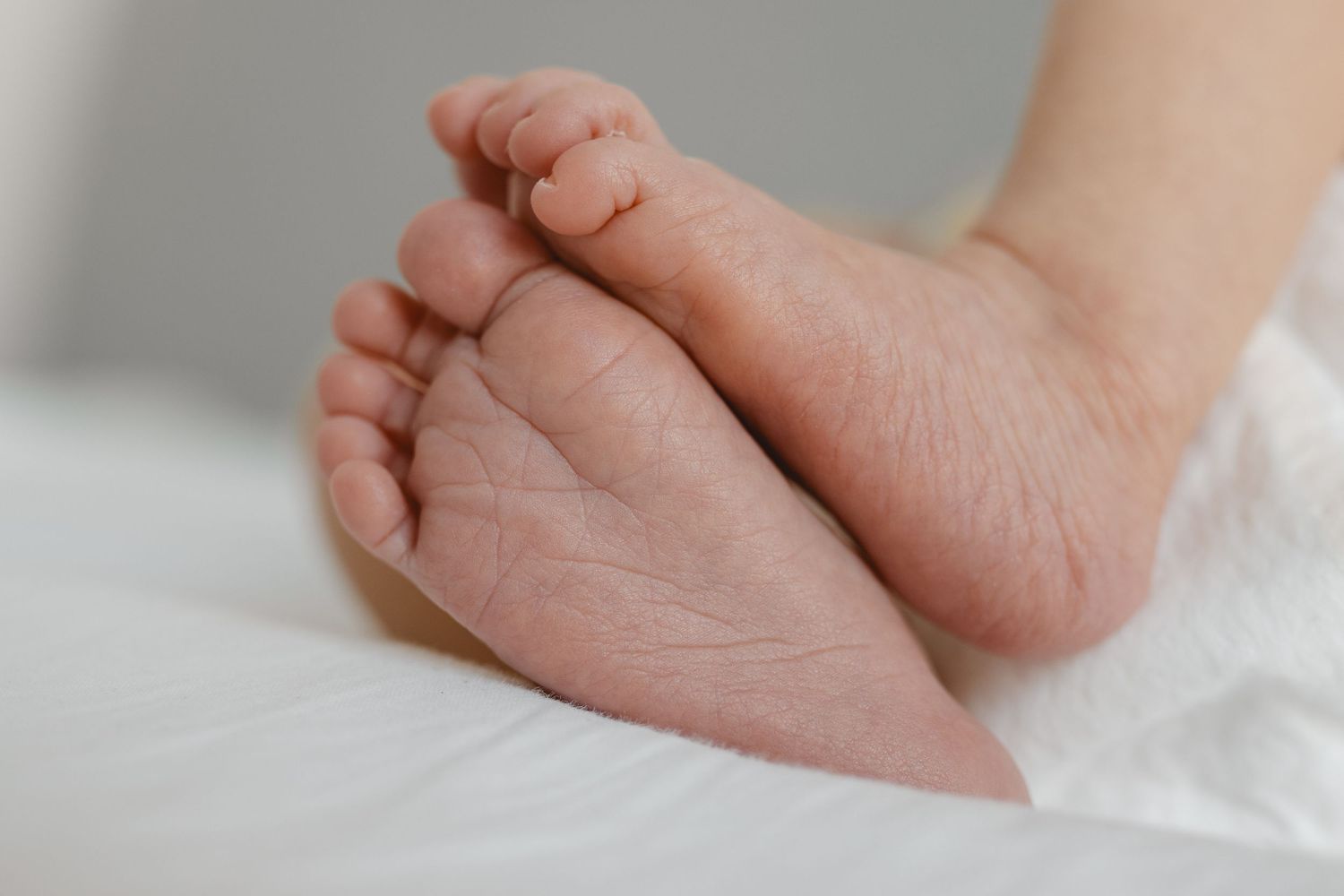 Tiny newborn baby's foot on a bed in Orange County.