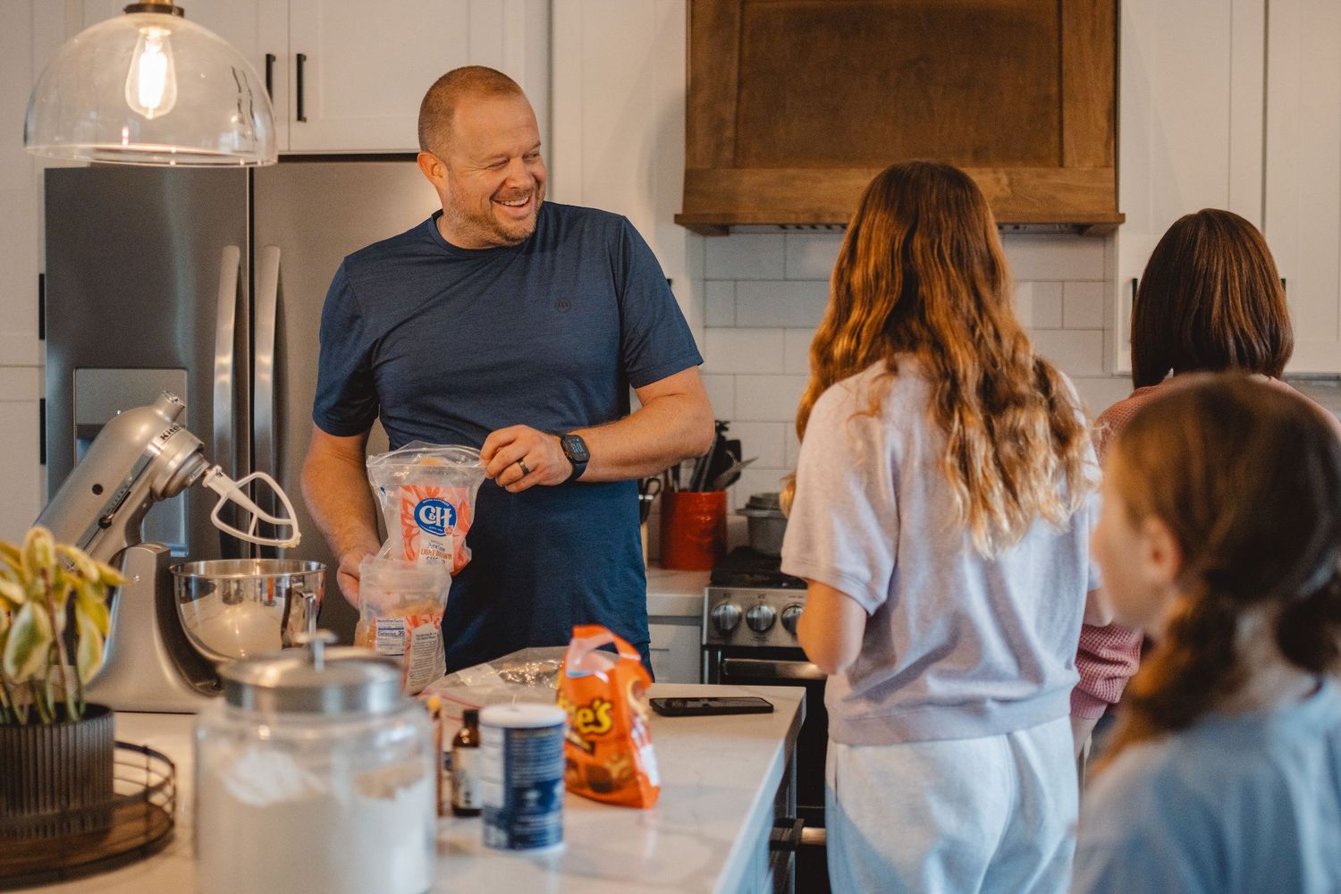 Family members gather in modern kitchen preparing food and spending time together around counter island in Newport Beach.
