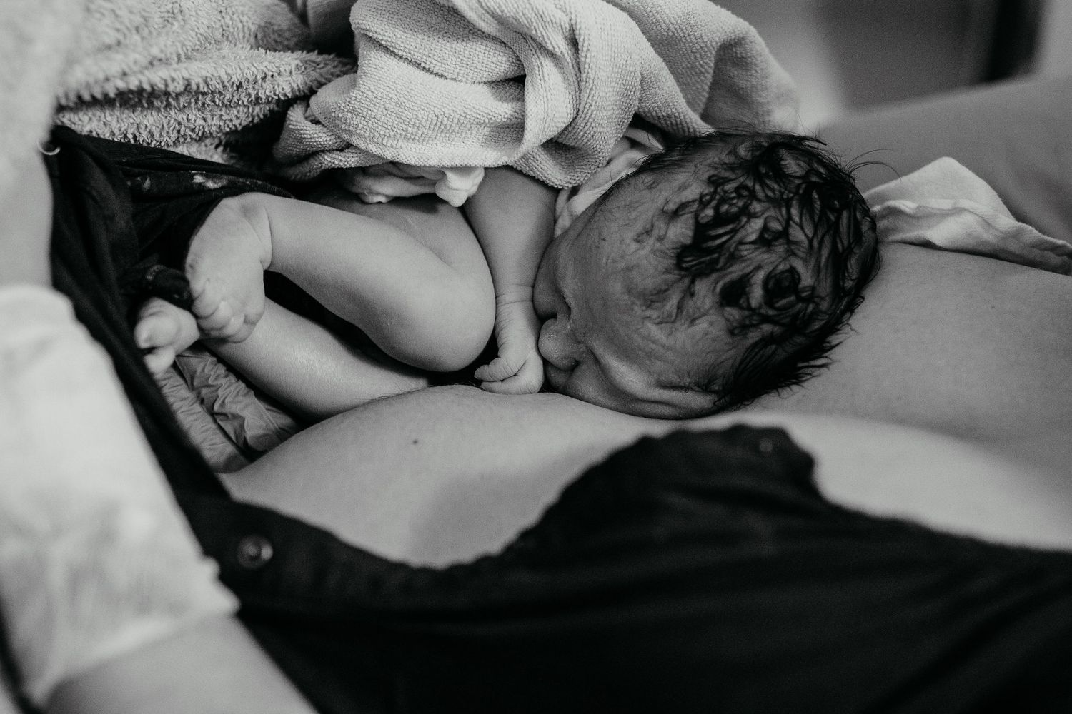 A few minutes old newborn lies sleeping on the mother’s chest in Newport Beach.