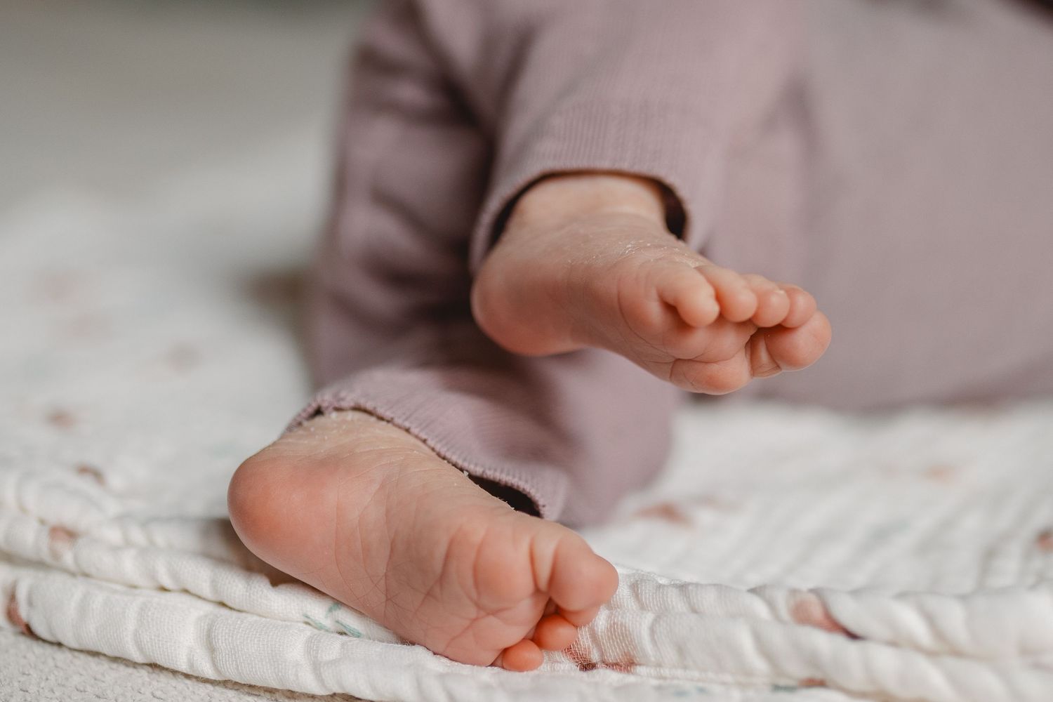 Close-up view of newborn baby feet resting on soft white textured fabric in Newport Beach.