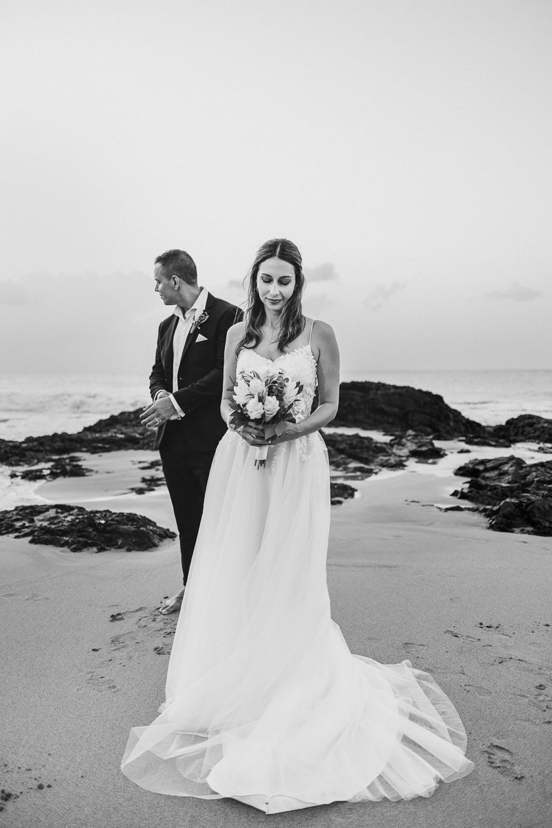 Black and white wedding photos of a couple on a rocky beach with dramatic coastal scenery in the background.