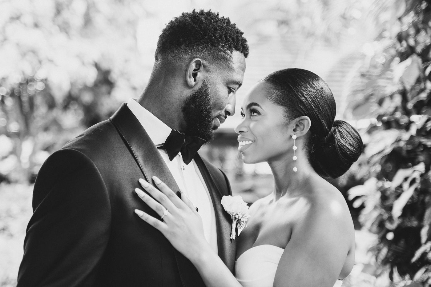 Intimate black and white portrait of newlyweds sharing romantic moments outdoors.