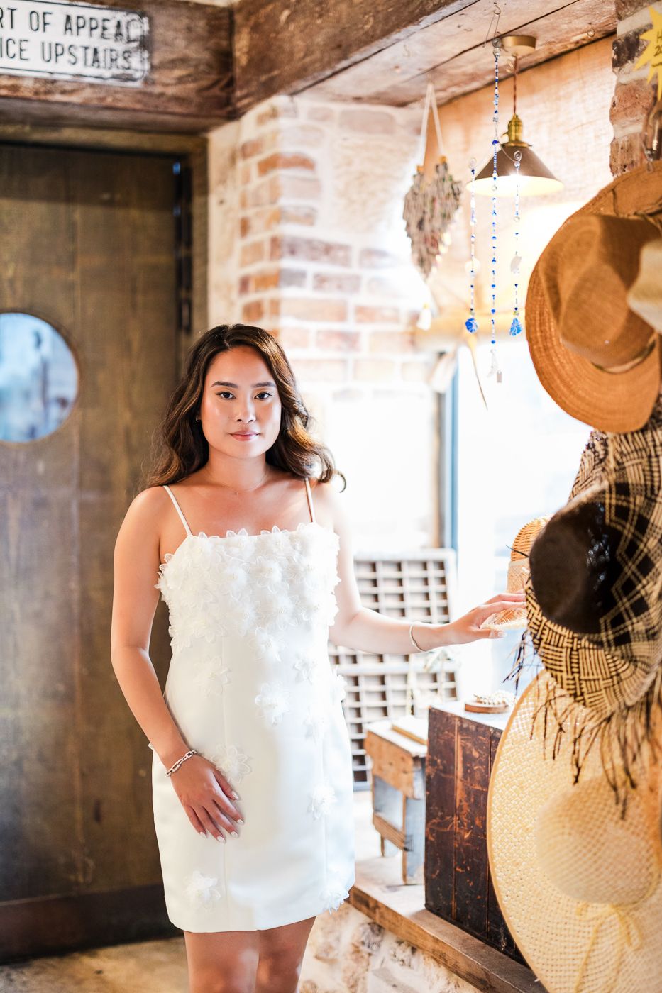 A white sundress stands out against rustic brick walls and vintage decor in a cozy interior.