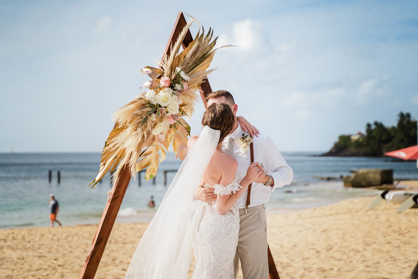 Romantic beach wedding ceremony capturing love in a white dress and suit under the tropical sky.