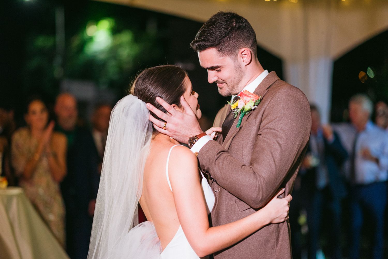 Couple shares an intimate moment during their first dance at a romantic dimly lit wedding reception.