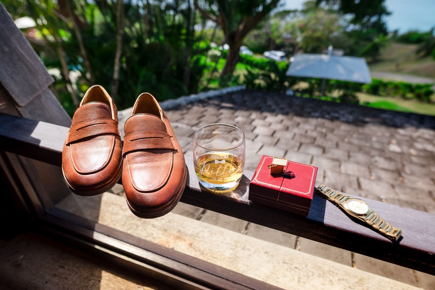Brown leather dress shoes and loafers arranged on wooden surface with accessories.