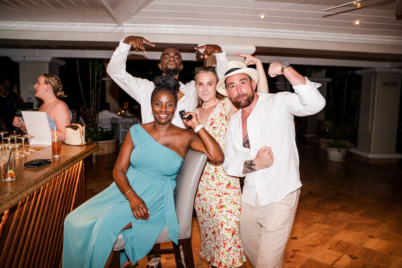 Wedding guests dancing and celebrating at a reception with wooden floors and ambient lighting.