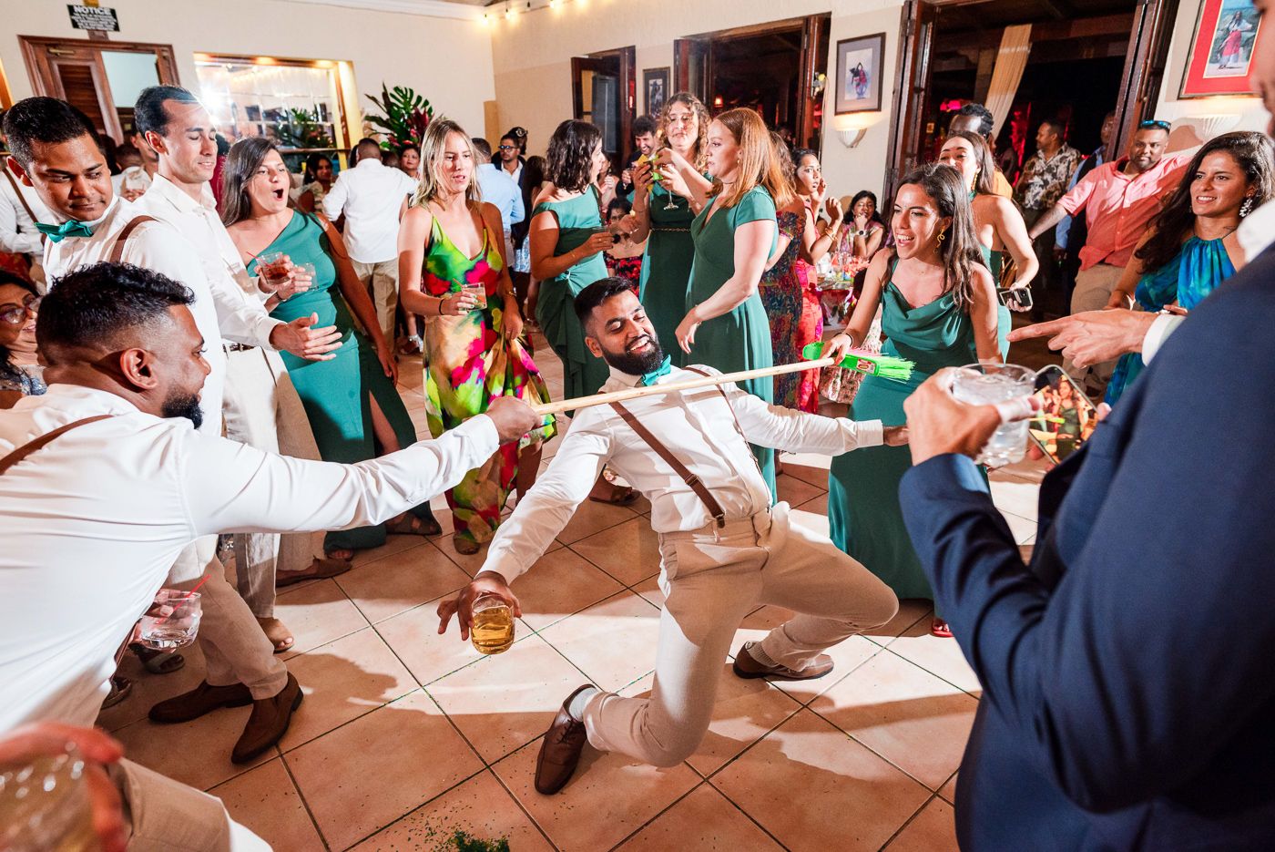 Wedding guests dance and celebrate energetically on a crowded dance floor during a reception party.