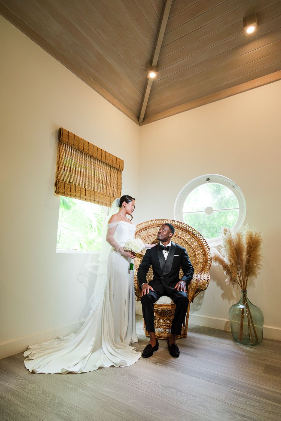 Romantic wedding portrait in minimalist room with peacock chair and dried pampas grass decor.