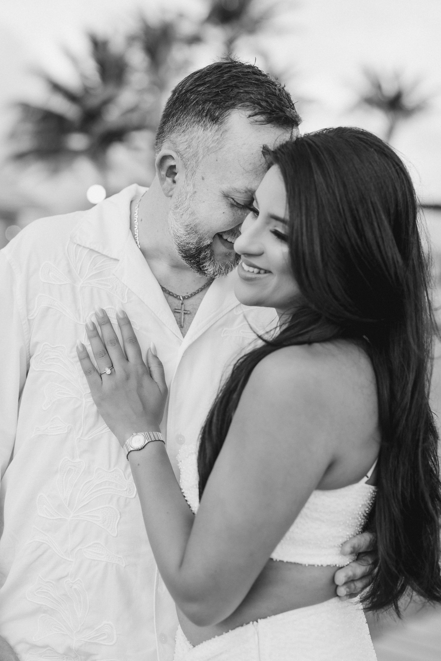 Black and white romantic portrait of a couple embracing and smiling together outdoors.