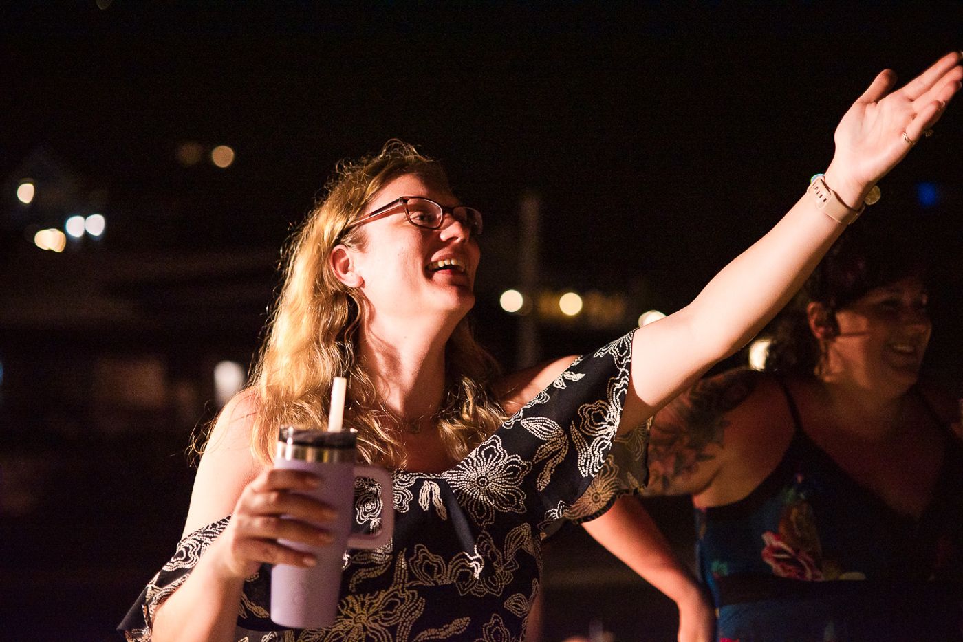 Person dancing joyfully at a nighttime party while holding a drink.