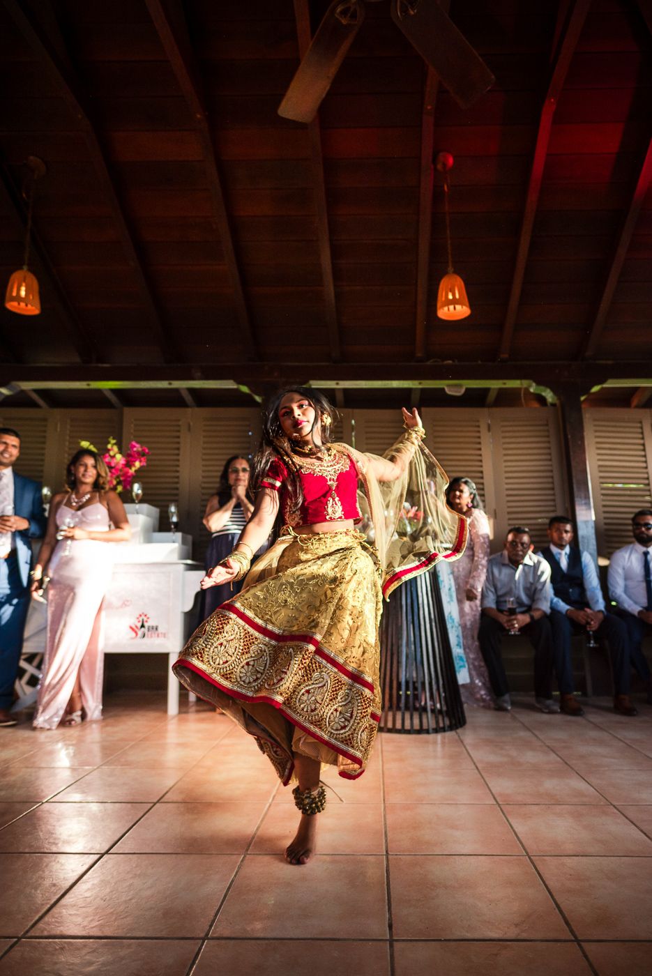 Traditional dance performance in ornate red and gold attire at wedding reception.