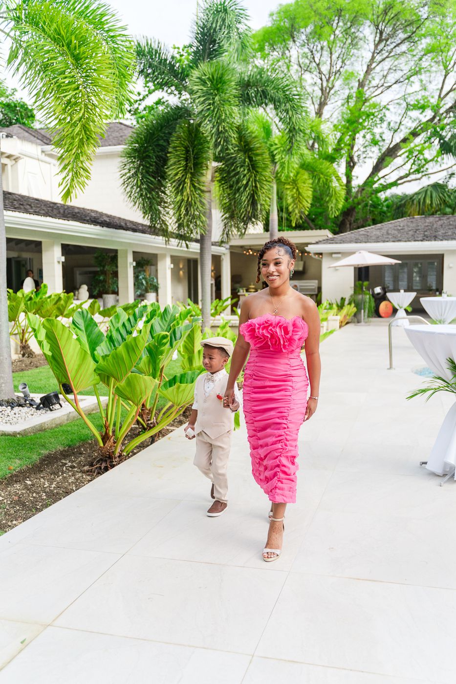 A person wearing pink moves energetically along a white pathway bordered by tropical palm trees.