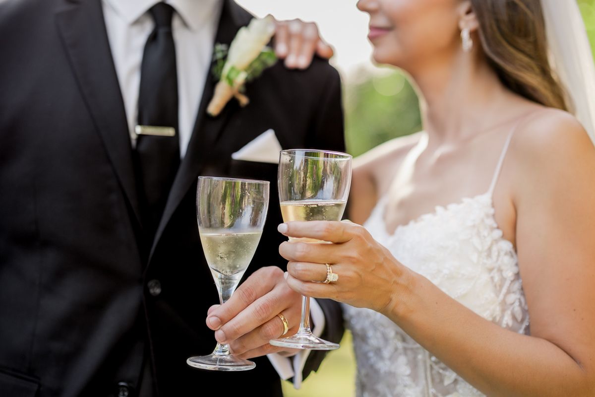 Bride and groom toasting with champagne flutes at outdoor wedding celebration.