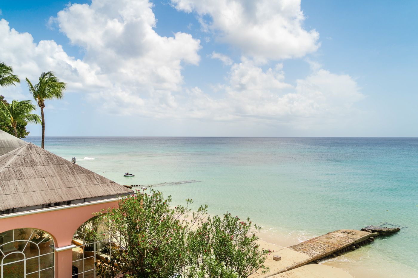 Beachfront luxury resort view with turquoise ocean waters, white sand beach and palm trees. Fairmont in barbados