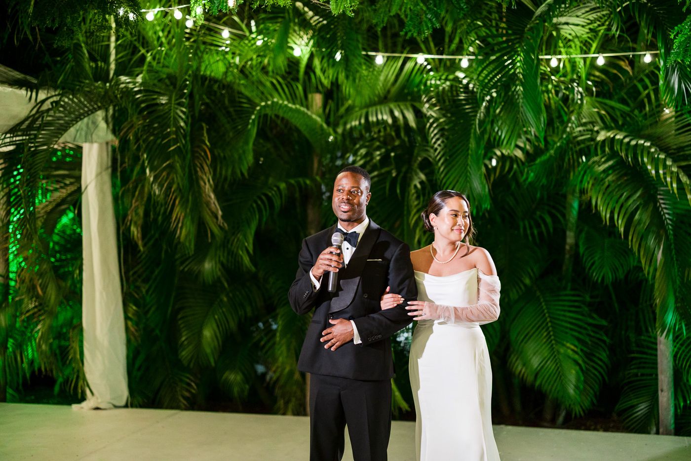 Romantic wedding ceremony moment under covered walkway surrounded by tropical greenery.