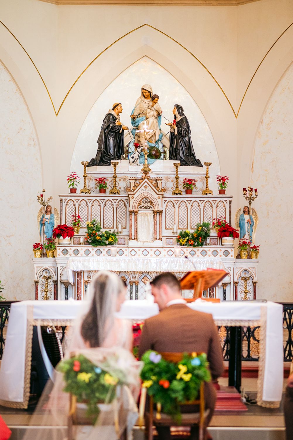 Beautifully decorated church altar with ornate architecture and floral arrangements during a wedding ceremony.