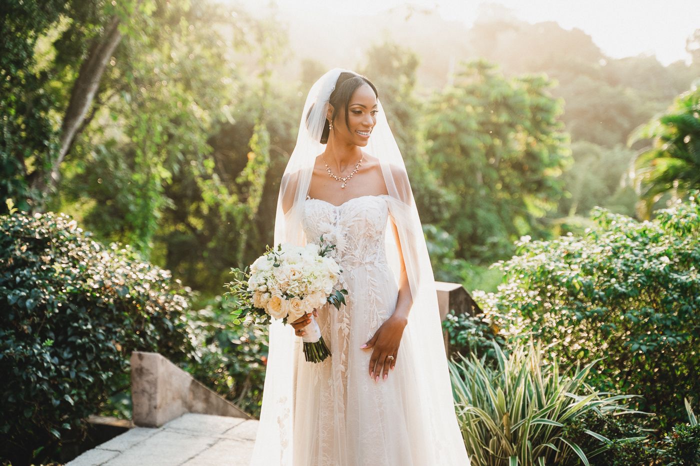 Sunlit garden wedding portraits among lush tropical greenery and flowers.