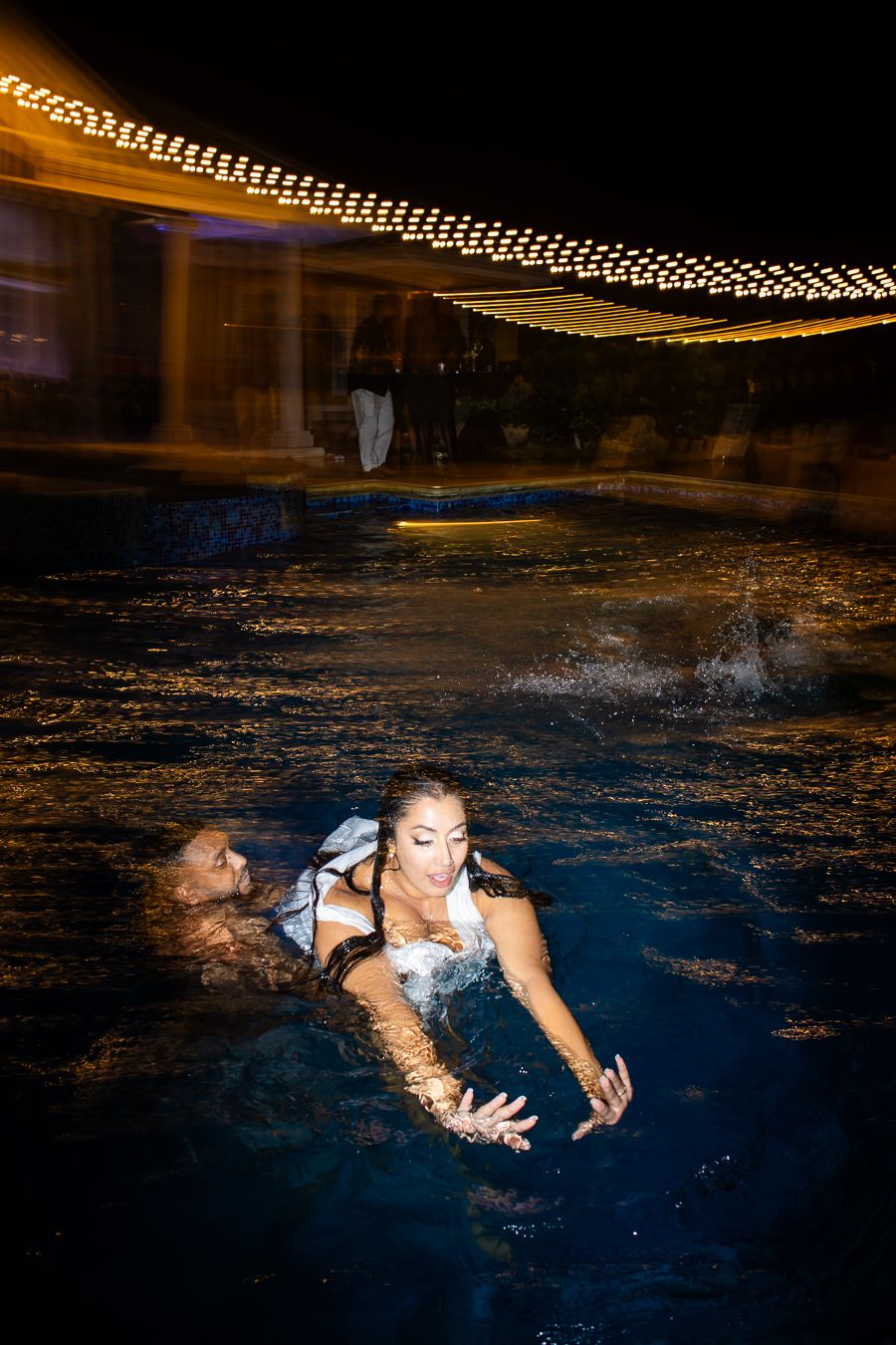 A dramatic photo series captures someone swimming in a dark pool with ambient lighting at night.