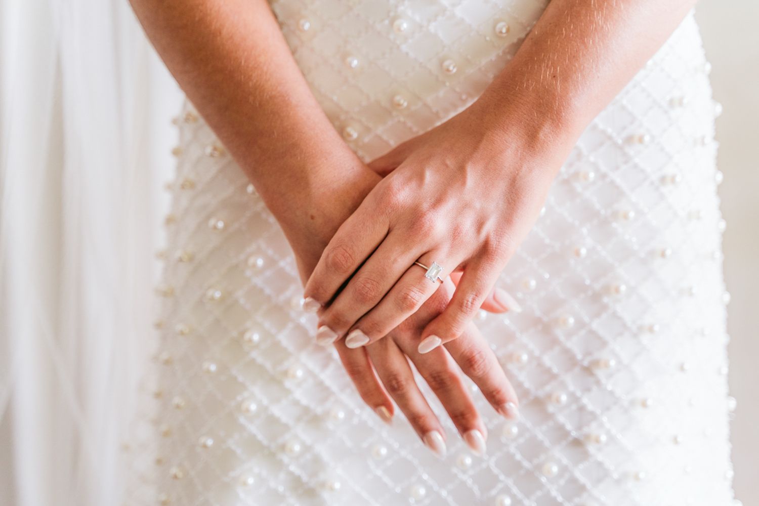 Closeup shot of hands resting on white lace fabric with delicate floral patterns.
