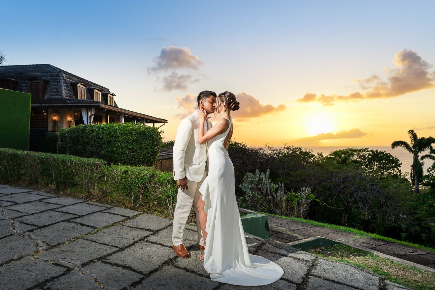 Newlyweds embrace on scenic stone patio during golden hour.
