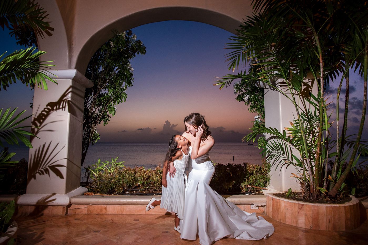 Romantic evening portrait at a tropical seaside wedding venue with arched architecture.