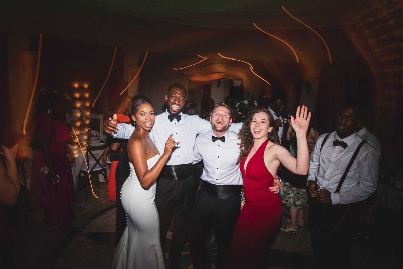 Wedding guests dancing and celebrating on the dance floor at an evening reception.