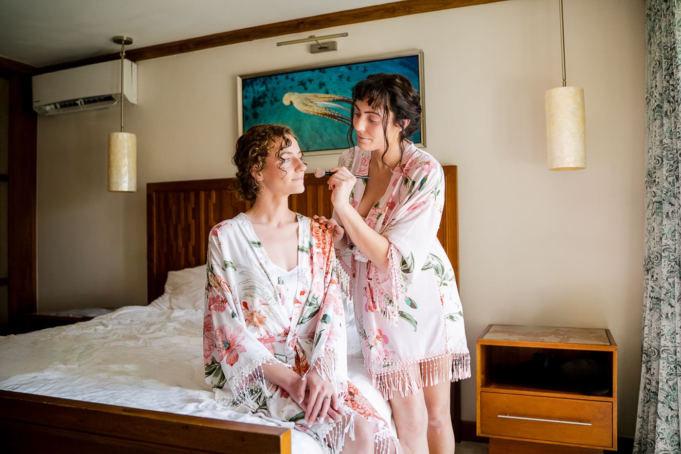 Two people in matching floral robes sharing a lighthearted moment in a bedroom.