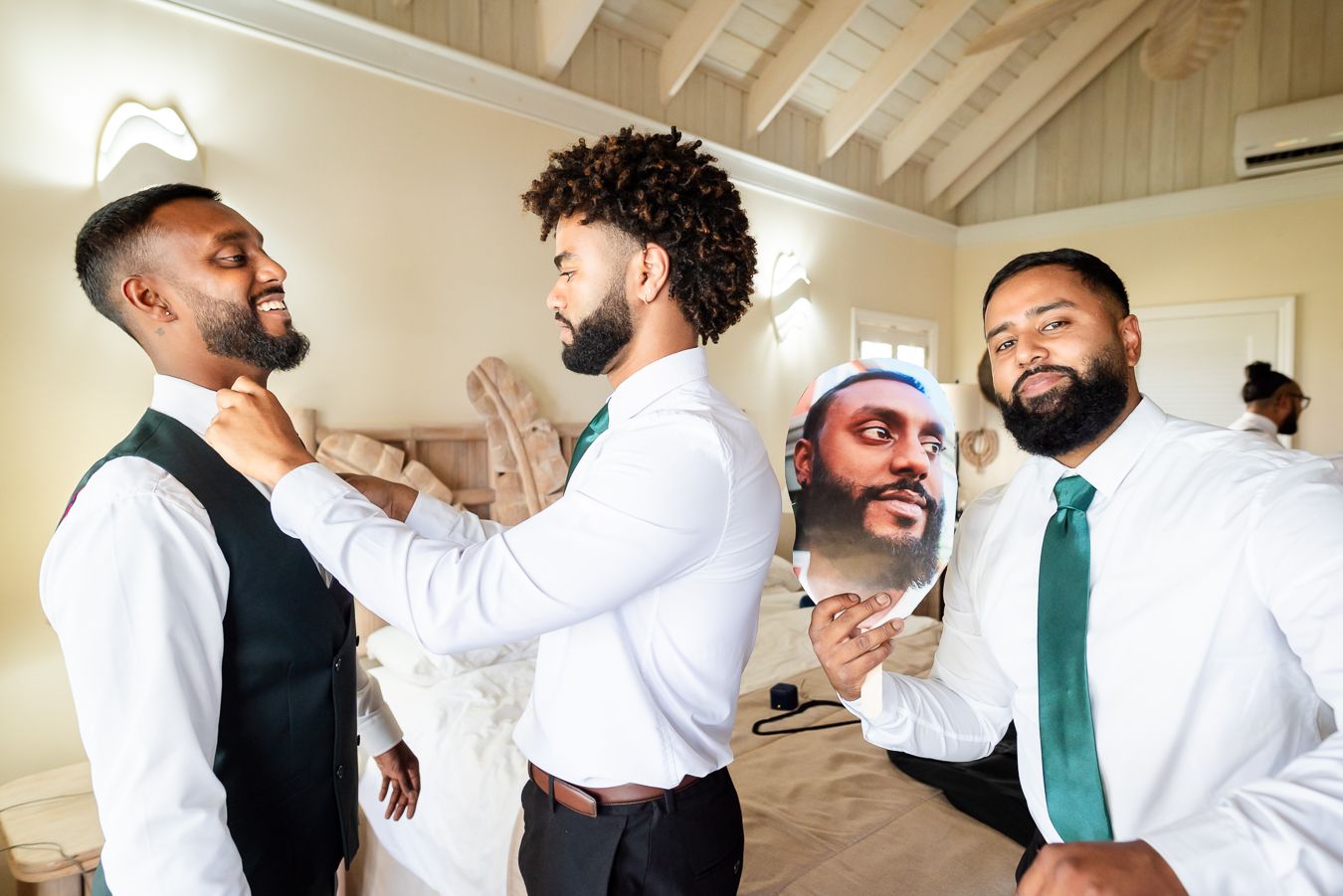 Wedding party members in vests and ties assisting each other with formal attire.