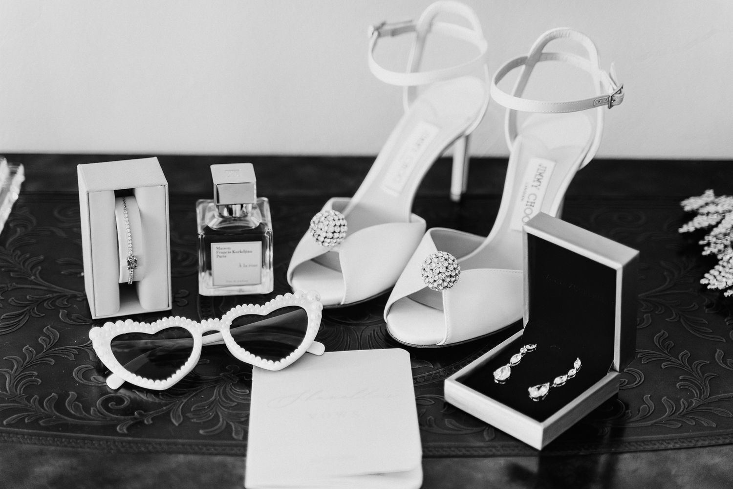 A collection of white Jimmy choo bridal shoes and accessories from different angles set against a black background.