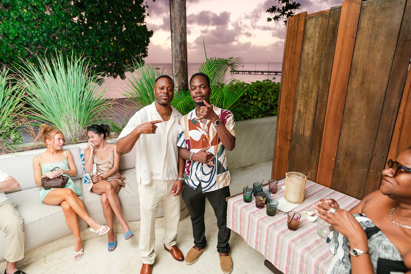 Wedding guests enjoy a casual outdoor reception on a tropical patio at sunset.