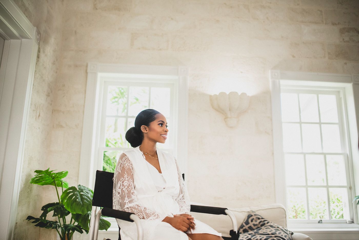 bride getting ready in white lace robe seated in bright, naturally lit room. black luxury wedding photography, Celeste and Reece