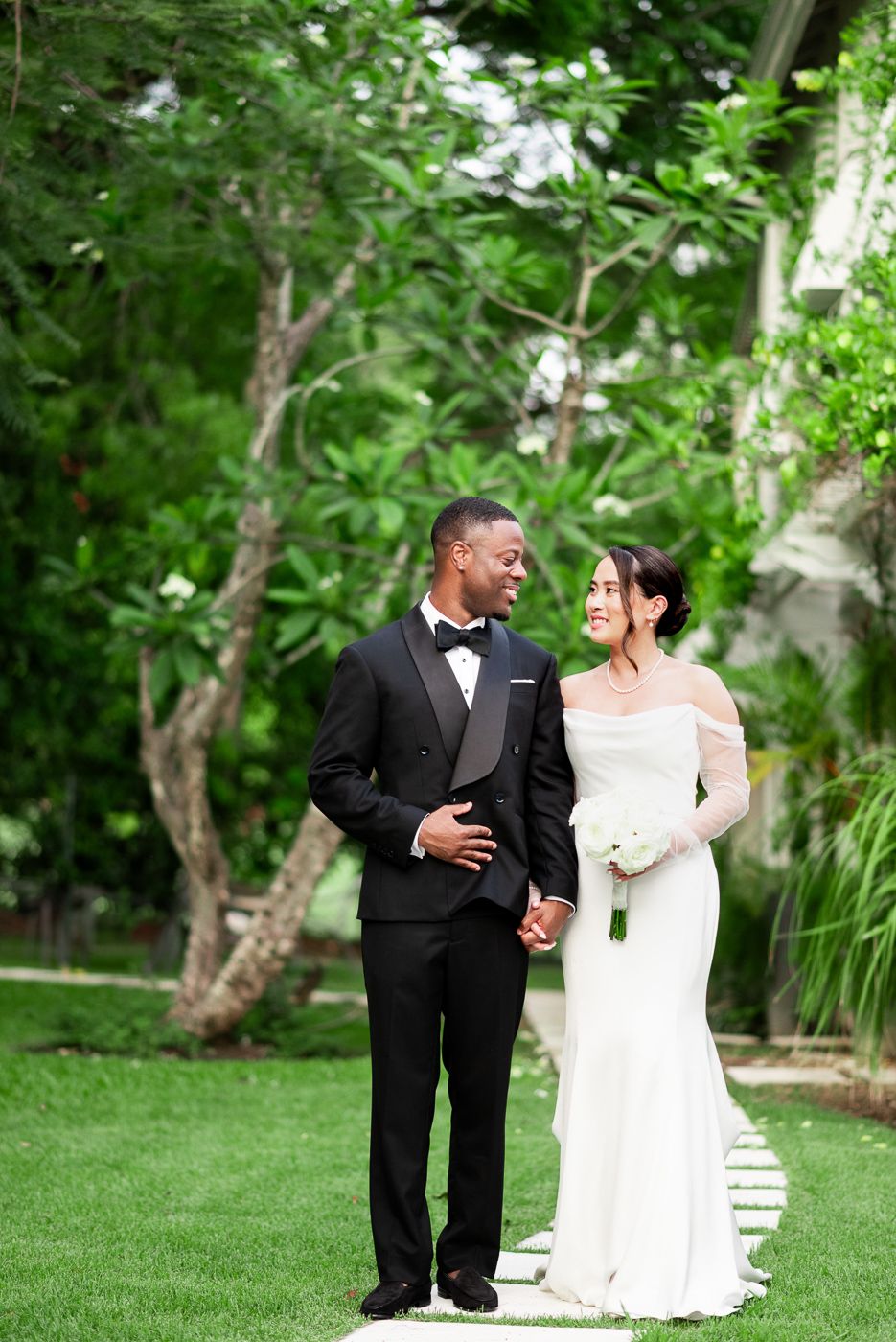 Newlyweds share a joyful moment together on their wedding day in a lush garden setting.