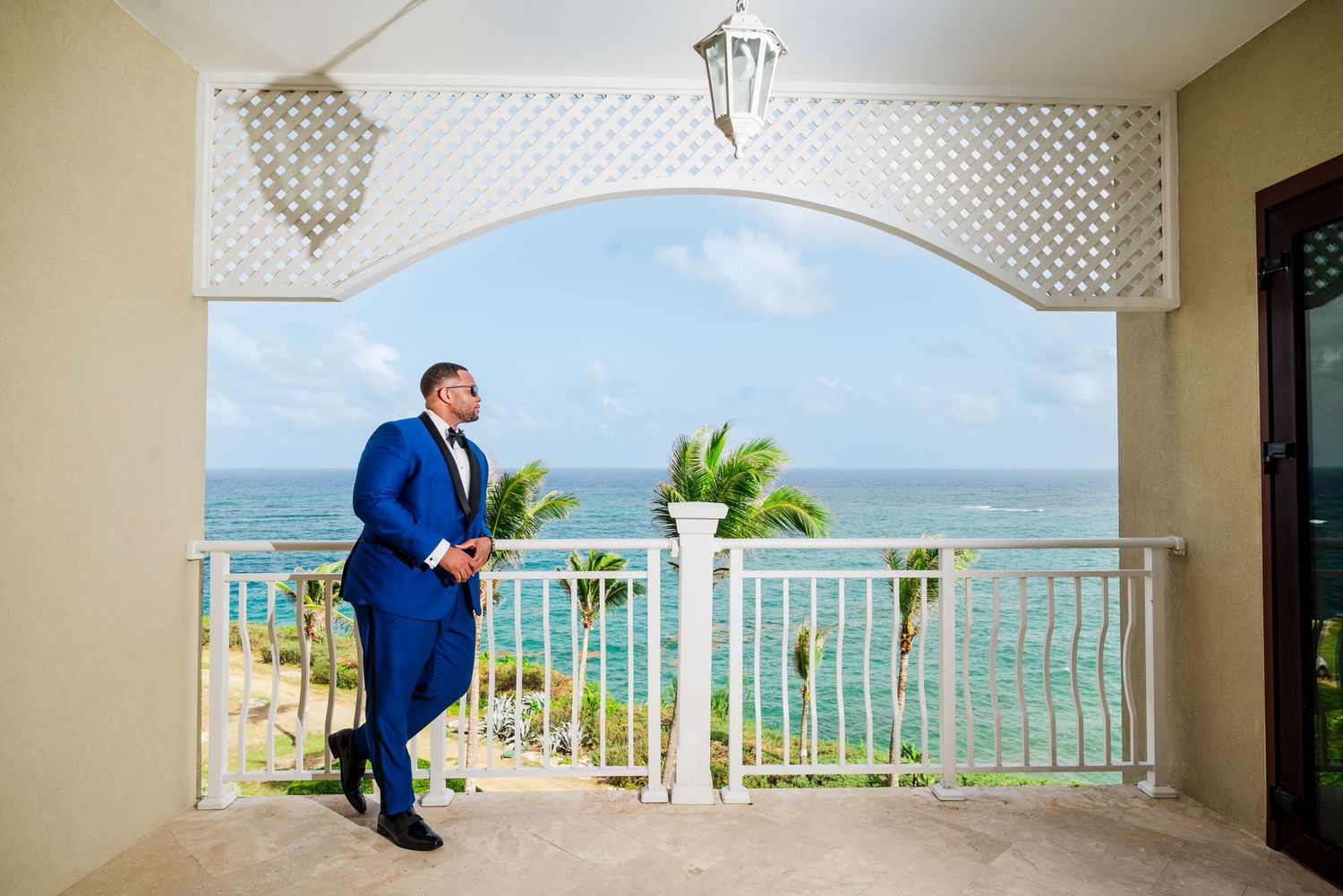 Panorama view of a balcony overlooking a beautiful tropical beach and ocean with white railings and palm trees, the crane resort barbados
