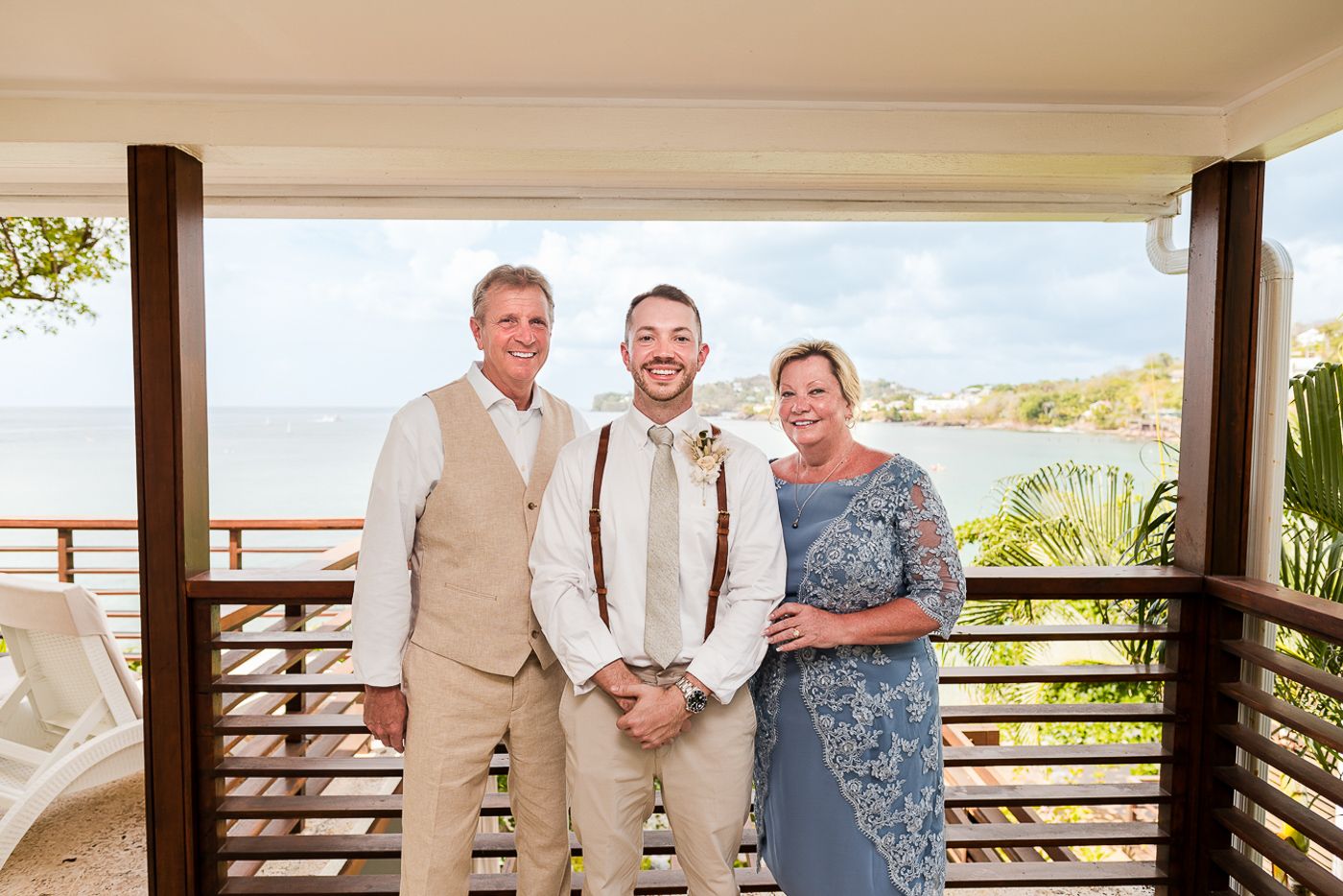 Group photo on a tropical balcony with wooden railings and ocean view.