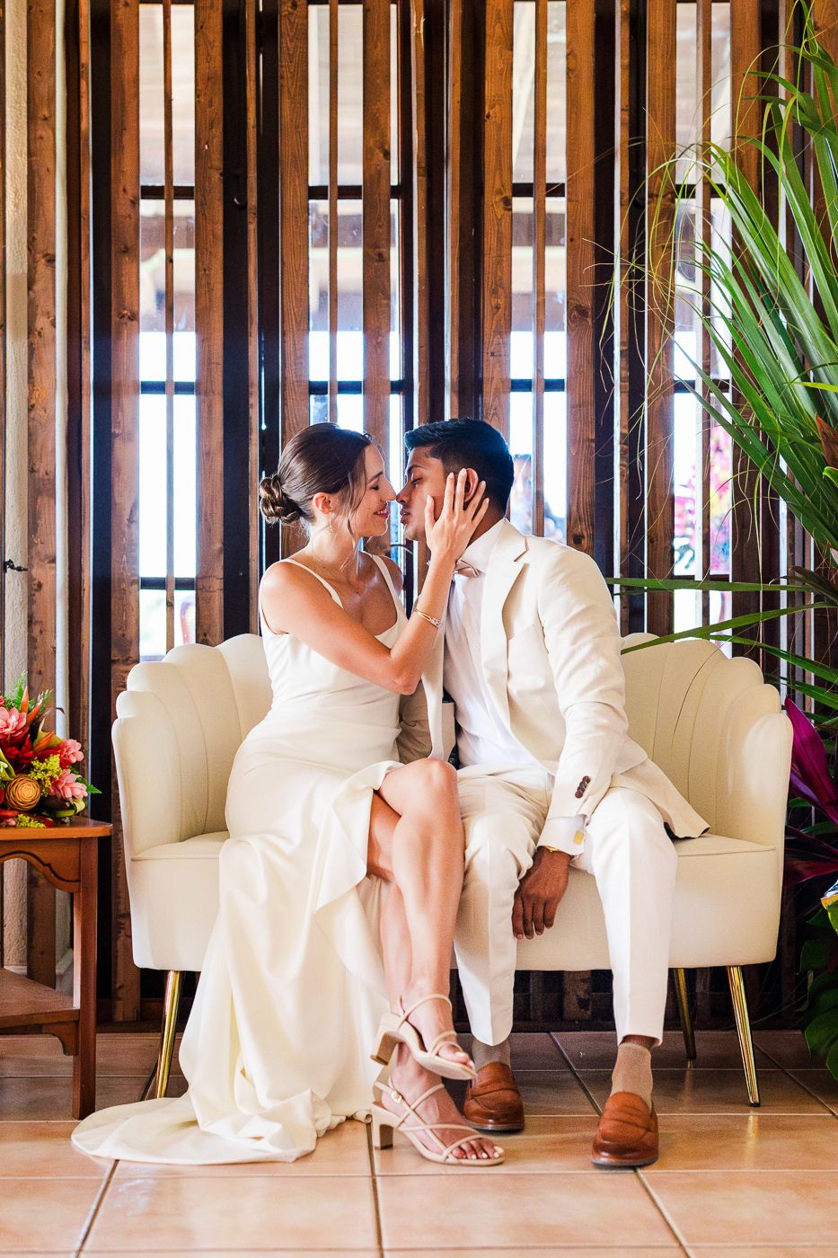 A romantic sequence of wedding photos featuring a couple sitting together on an elegant white couch indoors.