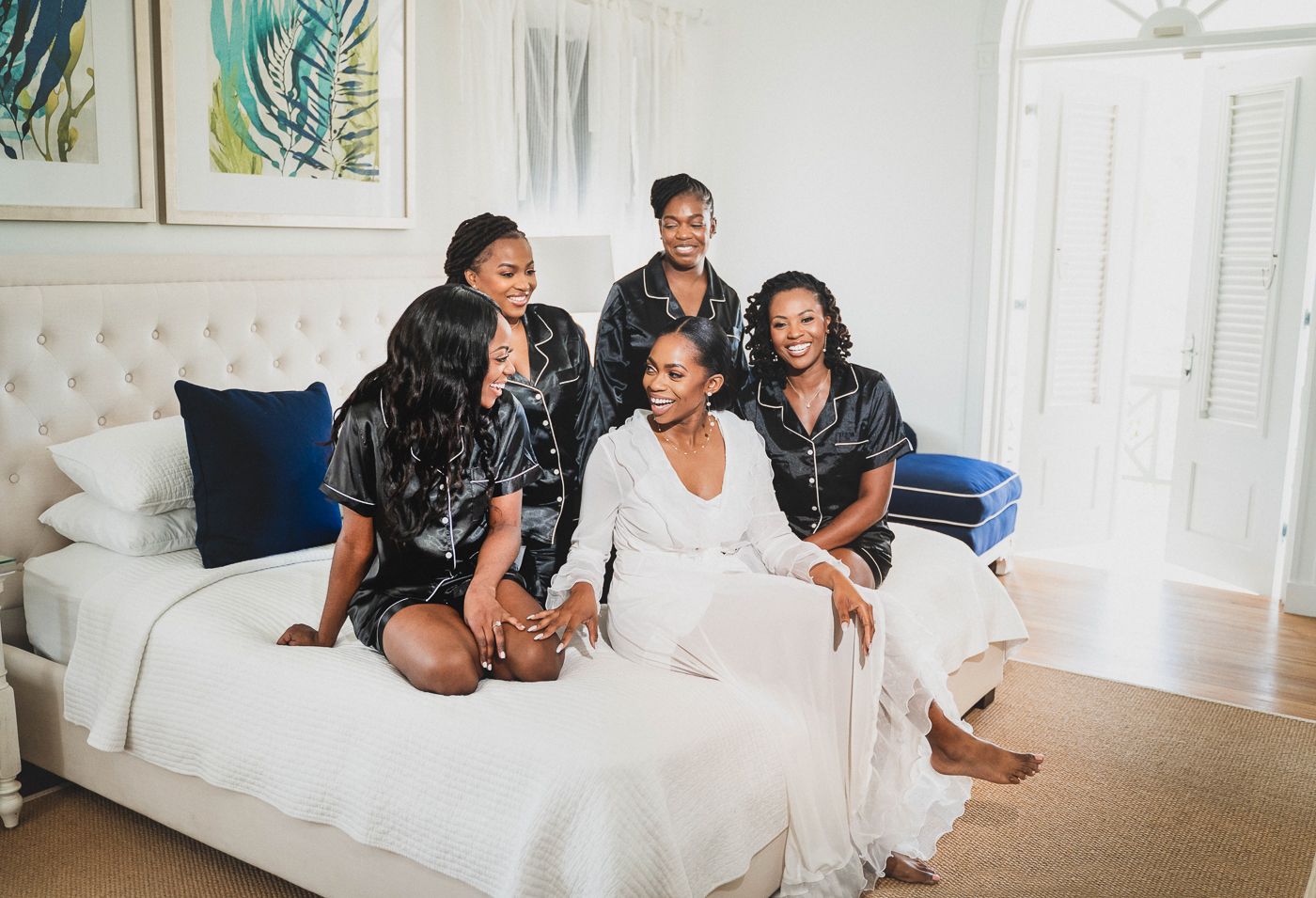 A group sharing a joyful moment together on a white bed with blue accent pillows.