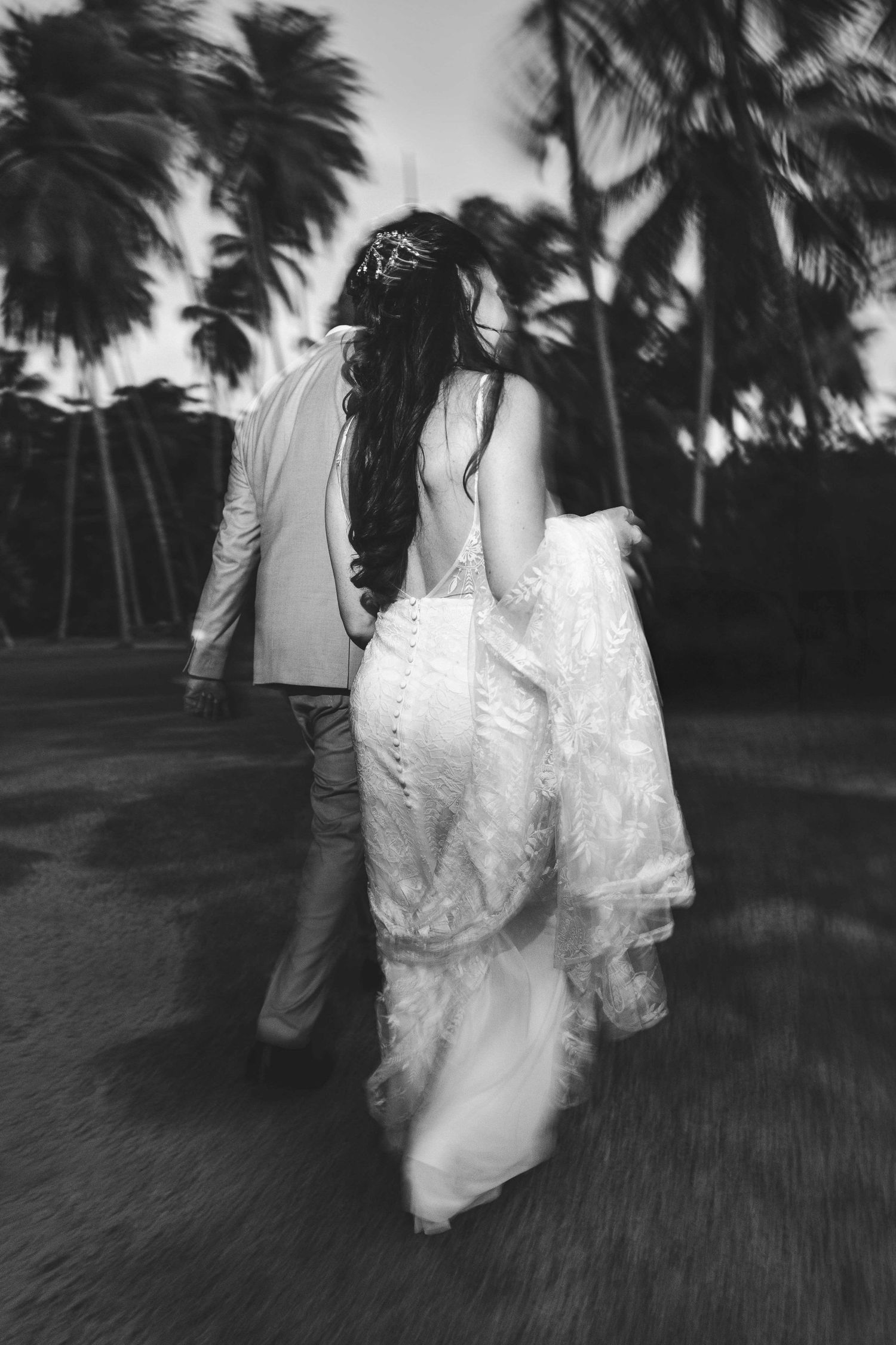Silhouetted figures in white attire walking among palm trees at dusk creating a dreamy atmosphere.