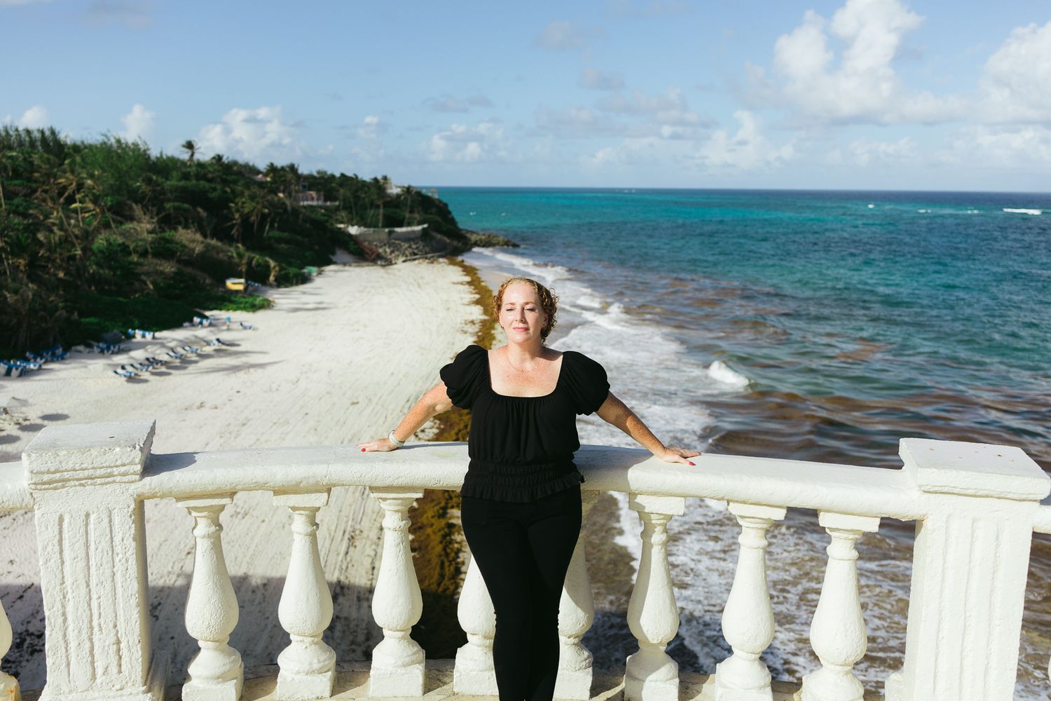 A sunny beachfront cliffside, white railings overlooking turquoise Caribbean waters and the crane beach resort barbados