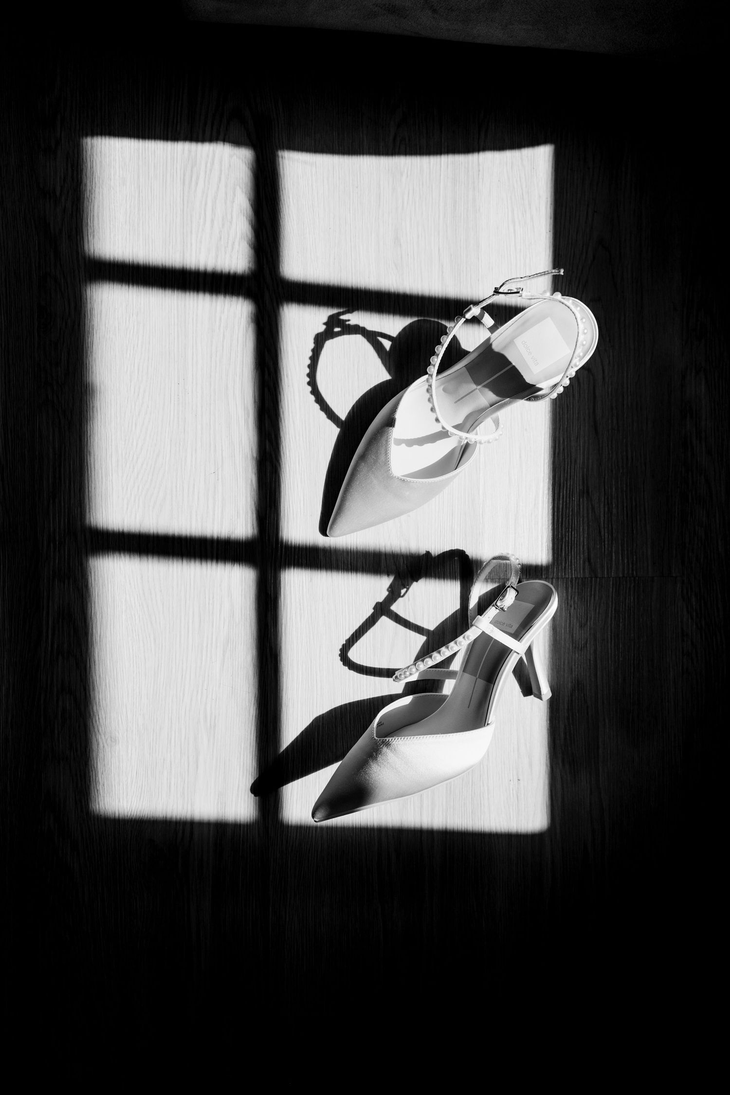 fine Art black and white photograph showing bright window light casting shadows with elegant white high heels, Celeste and Reece barbados