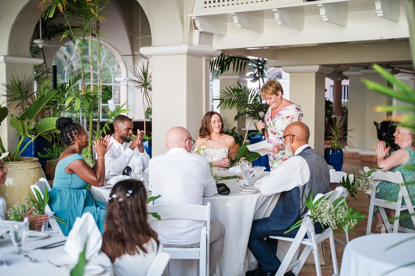 Wedding reception guests dine at tables on an elegant covered patio.