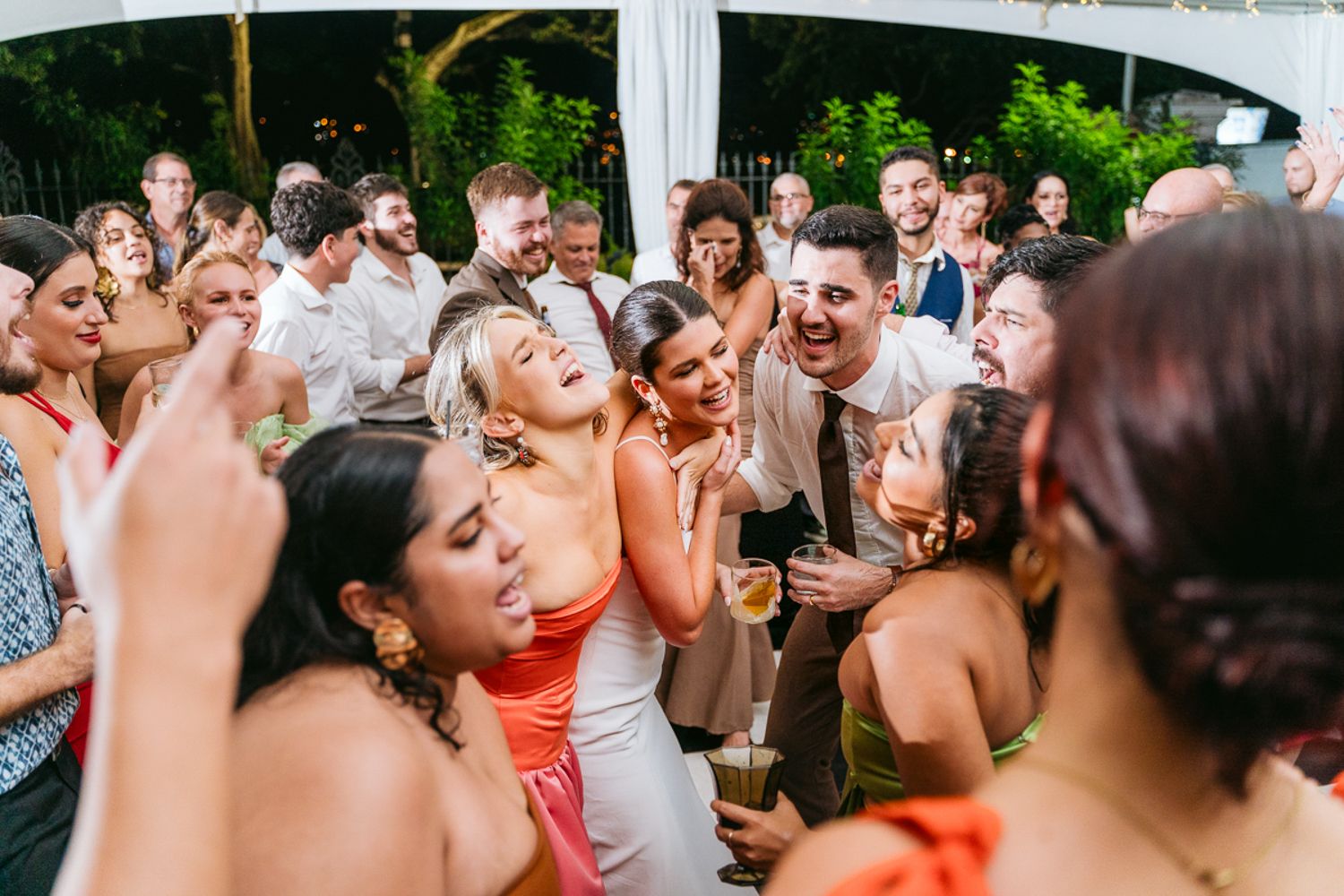 Wedding guests dance energetically together during a lively reception celebration on the dance floor.